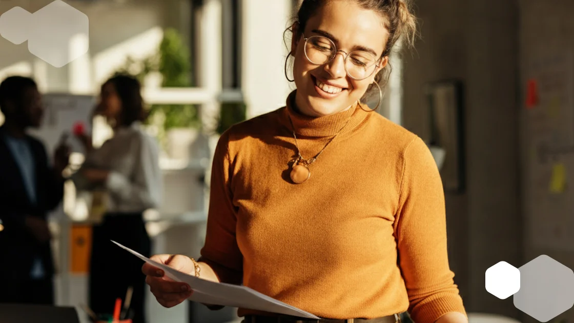 Healthcare professional reviewing documents with a smile in a modern office setting — EMR transcription integration concept.